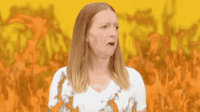 a woman is standing in front of a fire and making a funny face .