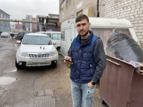 a man in a blue vest stands in front of a white suv with a license plate that says 204up