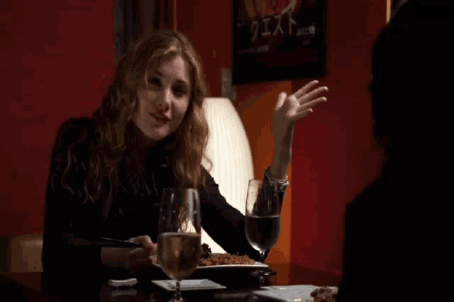 a woman sitting at a table with a plate of food and a glass of water