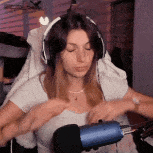 a woman wearing headphones and a white shirt is sitting in front of a blue microphone .