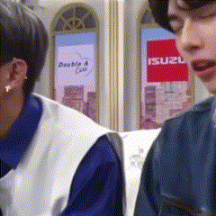 two people are sitting in front of a sign that says suzu