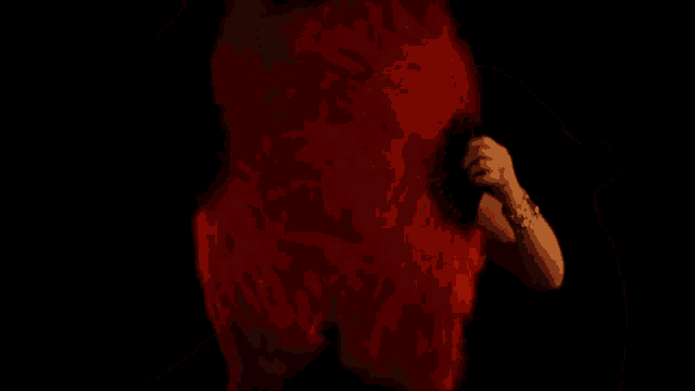 a woman in a black dress is holding a red feather in her hand