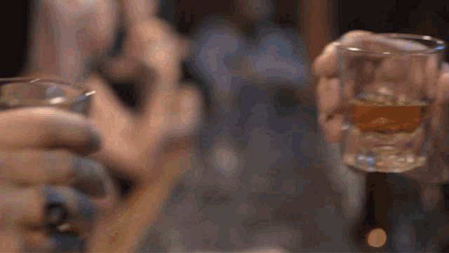 two people are holding shot glasses of whiskey in their hands