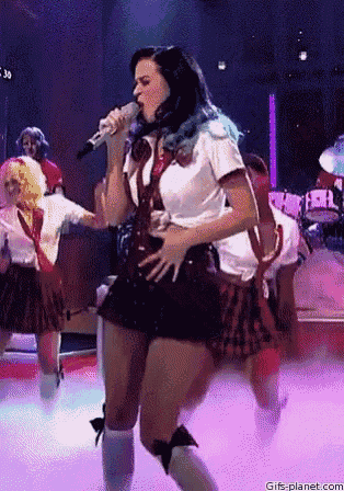a woman in a school uniform singing into a microphone on stage