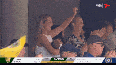 a woman holds a baby in her arms while watching a cricket match