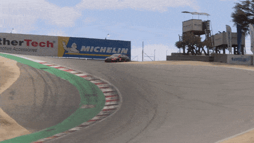 a race car is going down a track with a michelin sign in the background