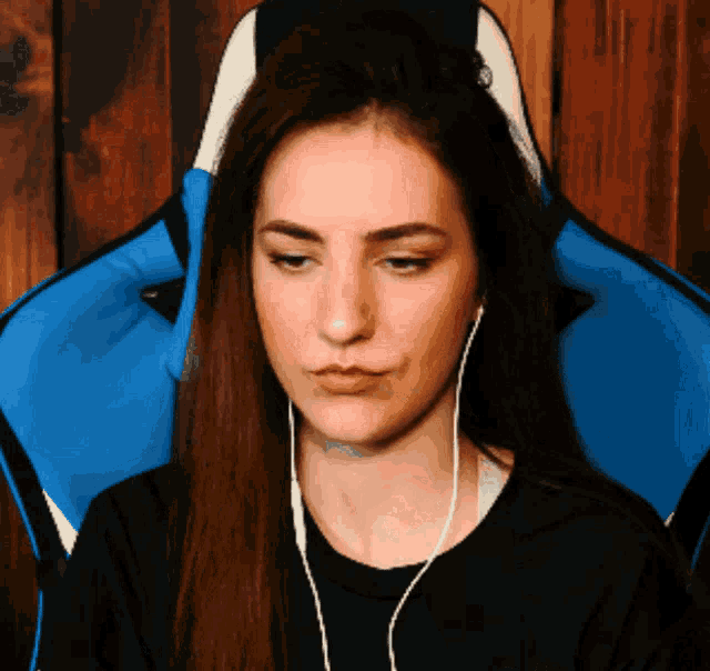 a woman wearing headphones sits in a blue and white gaming chair