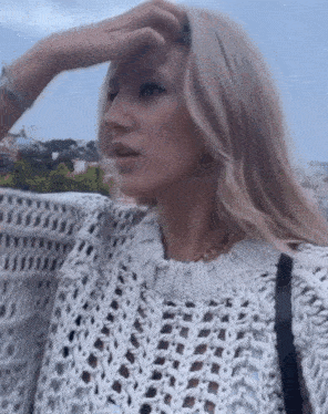 a woman wearing a white sweater covering her eyes