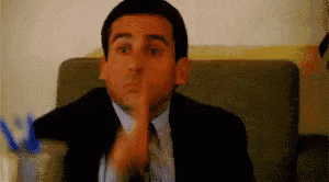 a man in a suit and tie is sitting on a couch and making a funny face .