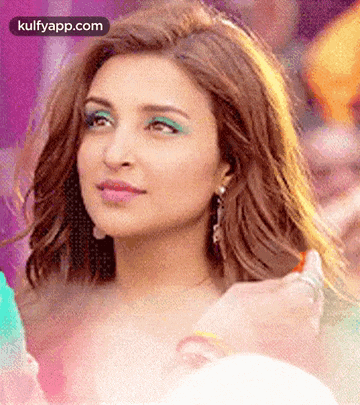 a close up of a woman 's face with green eye shadow and earrings .