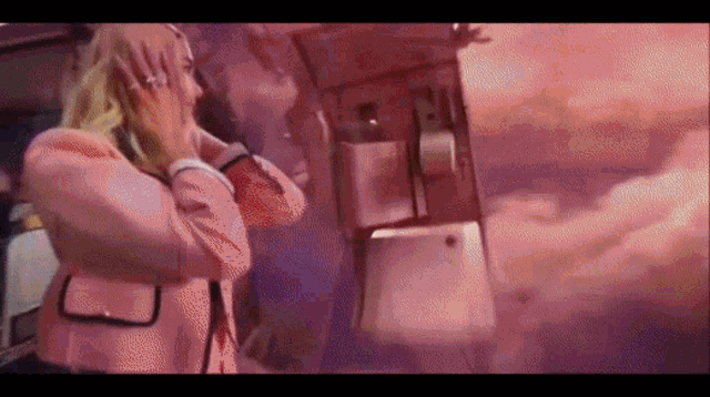 a woman in a pink jacket talks on a phone