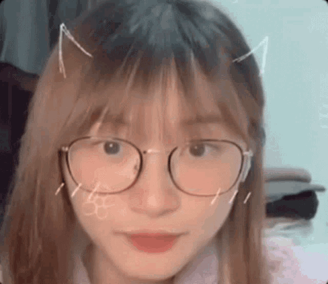 a close up of a girl wearing glasses and cat ears on her head .