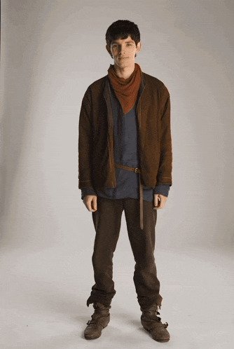 a young man wearing a brown jacket and brown pants stands in front of a white background