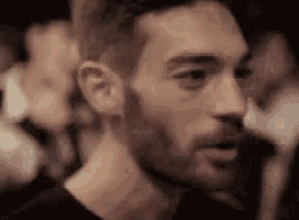 a close up of a man 's face with a beard and a black shirt .