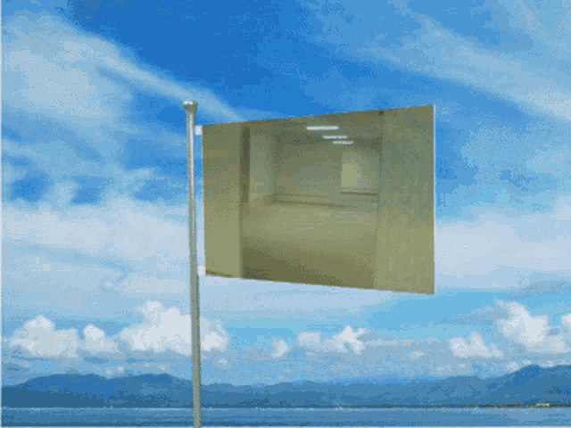 a flag is flying in the wind in front of a body of water