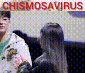 a man and a woman are talking in front of a sign that says chismosavirus