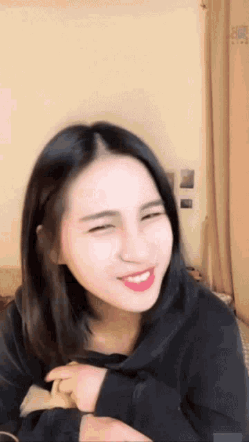 a woman in a black shirt is smiling and making a face