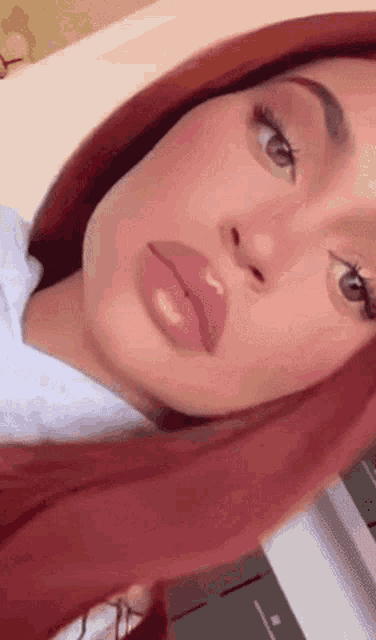 a close up of a woman 's face with red hair and lipstick .