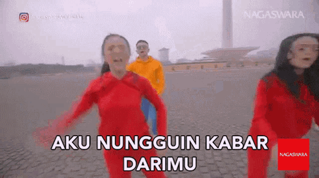 a group of people in red jumpsuits are dancing in front of a sign that says ' aku nungguin kabar darimu '