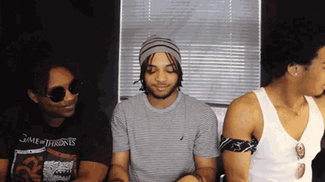 a man wearing a game of thrones t-shirt sits next to two other men