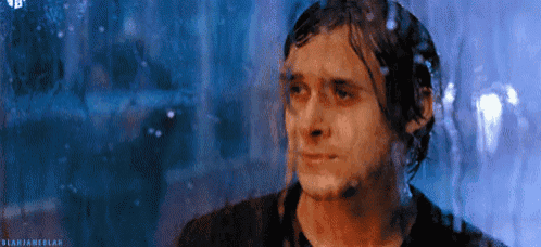 a man is standing in front of a window with water coming out of it .