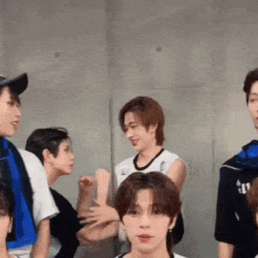 a group of young men are standing next to each other in a room and talking .