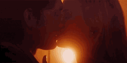 a man and a woman are kissing in front of a sunset in a dark room .