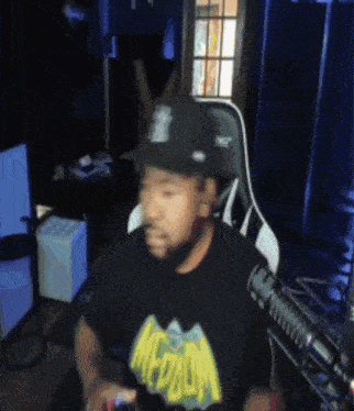 a man wearing a hat and a shirt that says medium is sitting in front of a microphone