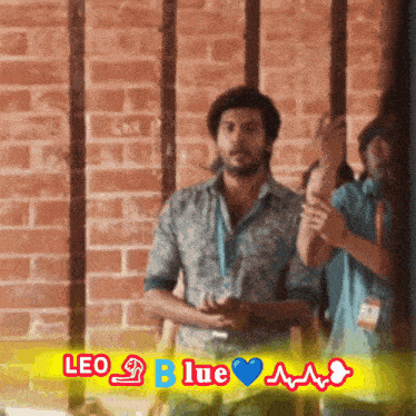 a man in a blue shirt is standing in front of a brick wall with the words leo blue written above him