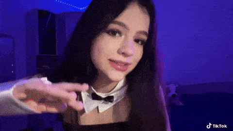 a girl with long dark hair is wearing a bow tie and a black dress .
