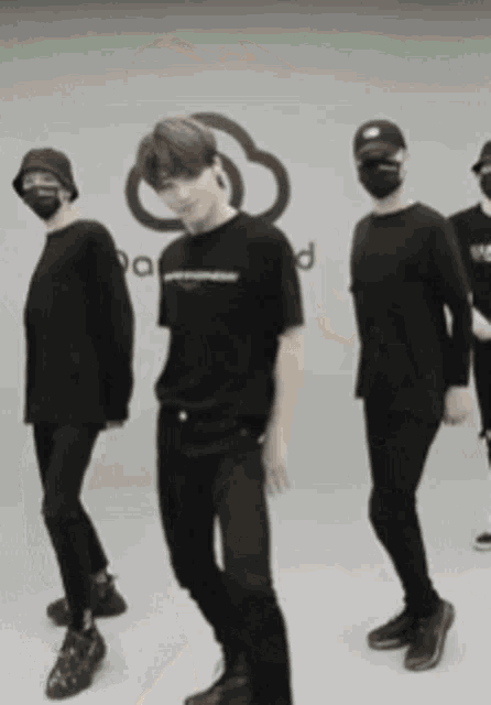 a group of people wearing face masks are dancing in front of a wall that has the word cloud on it