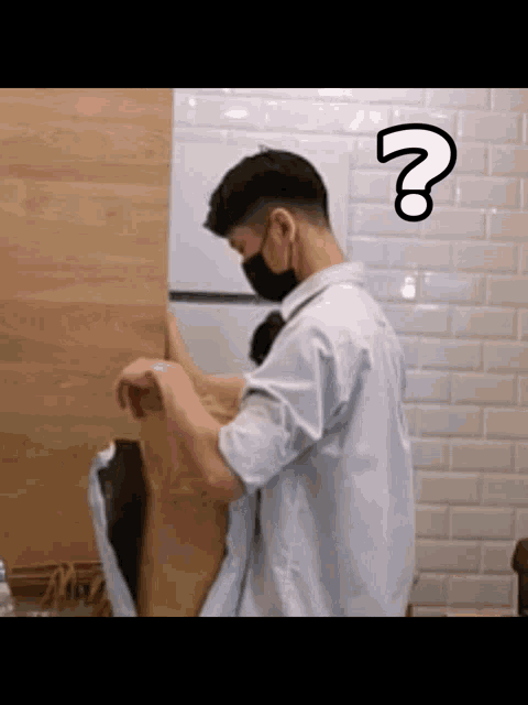 a man wearing a mask is standing in front of a wooden wall with a question mark on his forehead .
