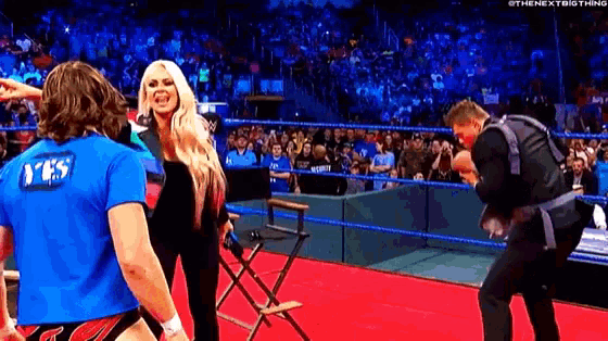 a man in a blue shirt is standing next to a woman in a wrestling ring .