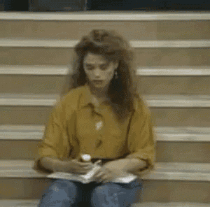 a woman in a yellow shirt is sitting on a set of stairs holding a cell phone .