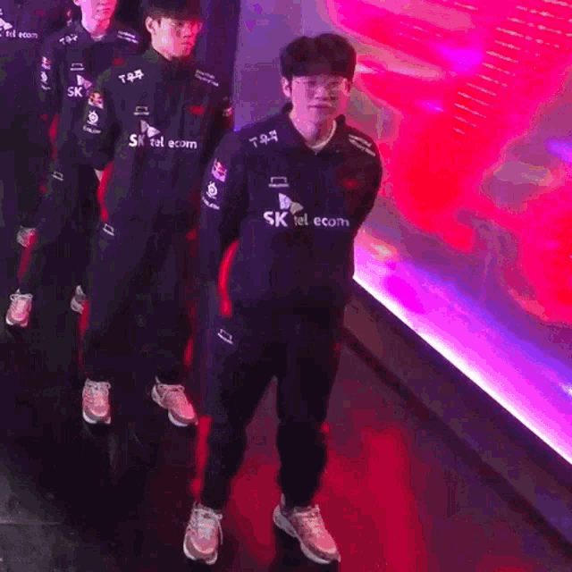 a man wearing a sk telecom jacket stands in a line