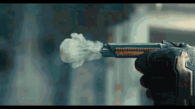 a person holding a gun with smoke coming out of the barrel