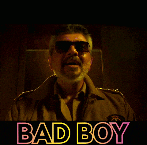 a man wearing sunglasses stands in front of a sign that reads bad boy