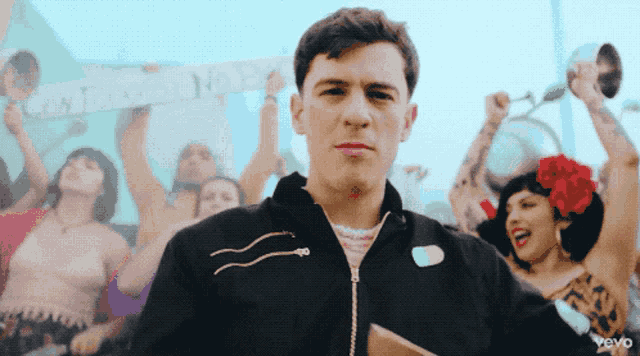 a man in a black jacket stands in front of a crowd holding a sign that says castañedo no y