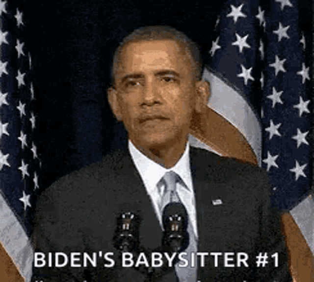 barack obama is giving a speech at a podium in front of american flags .