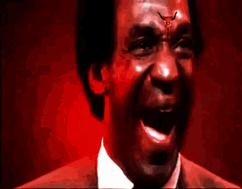 a man with a bull on his forehead is laughing with his mouth open