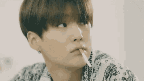 a close up of a person smoking a cigarette in a bandana shirt .