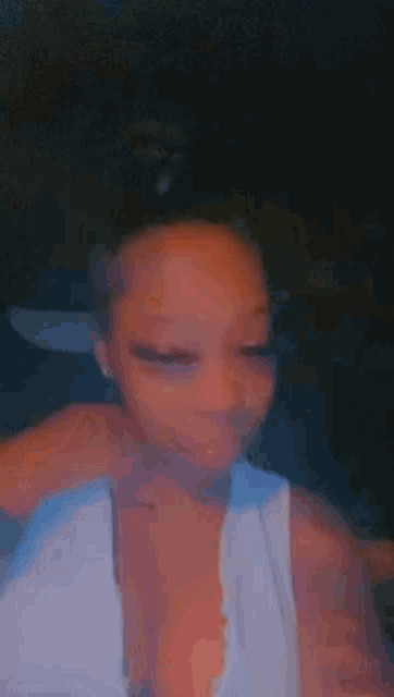 a woman in a white tank top is taking a picture of herself .
