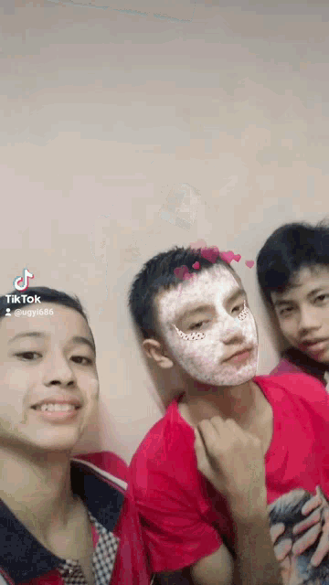 three boys are posing for a picture and one has a face mask on
