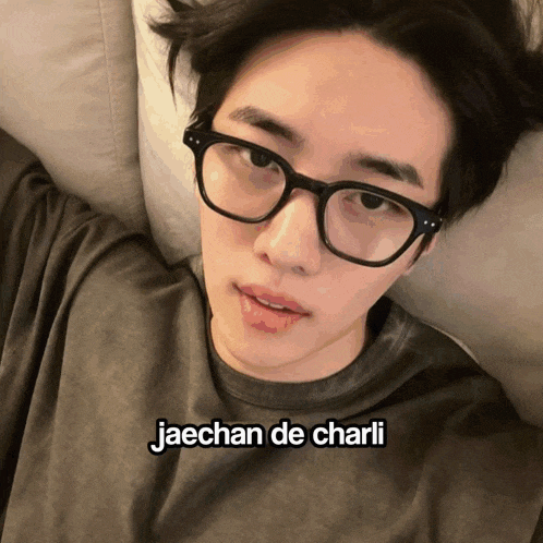 a young man wearing glasses is laying on a couch with the caption jaechan de charli