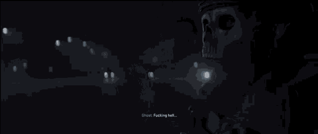 a man with a skull on his face is standing in the dark and talking .