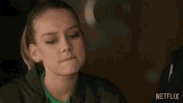 a woman in a green jacket with netflix written on the bottom right