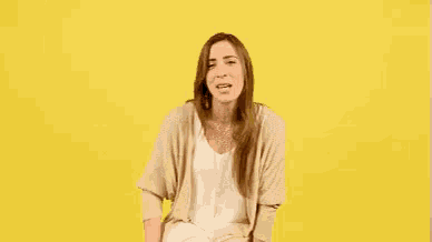 a woman is sitting on a yellow chair and smiling .