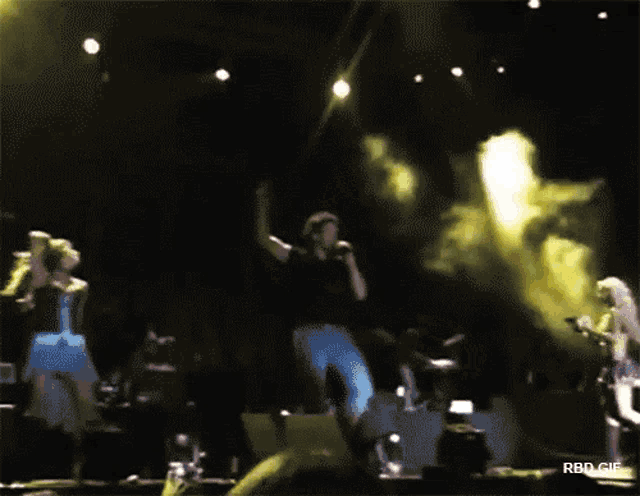 a blurry photo of a group of people dancing on a stage with rbd.gif below them