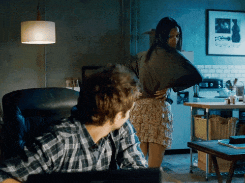 a man in a plaid shirt is looking at a woman in a skirt in a kitchen