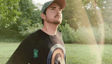 a man wearing a captain america t-shirt stands in a field